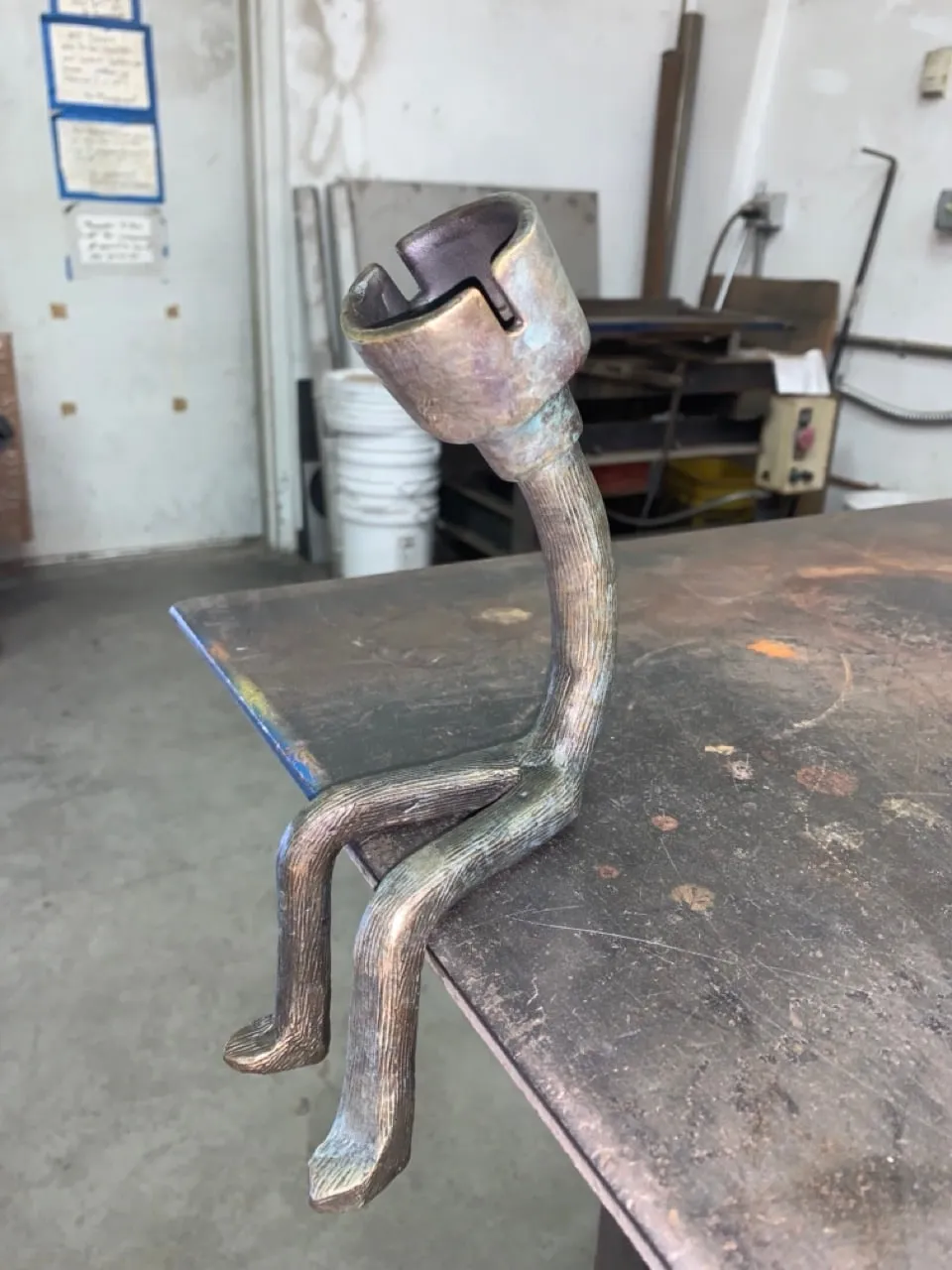 The figure in bare bronze on a steel workbench