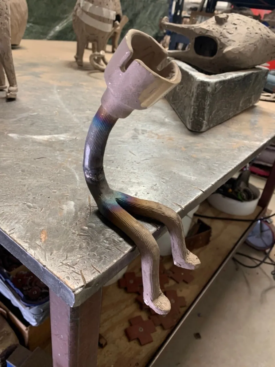 The cast figure on a foundry bench, with heat colouring at the neck and hips