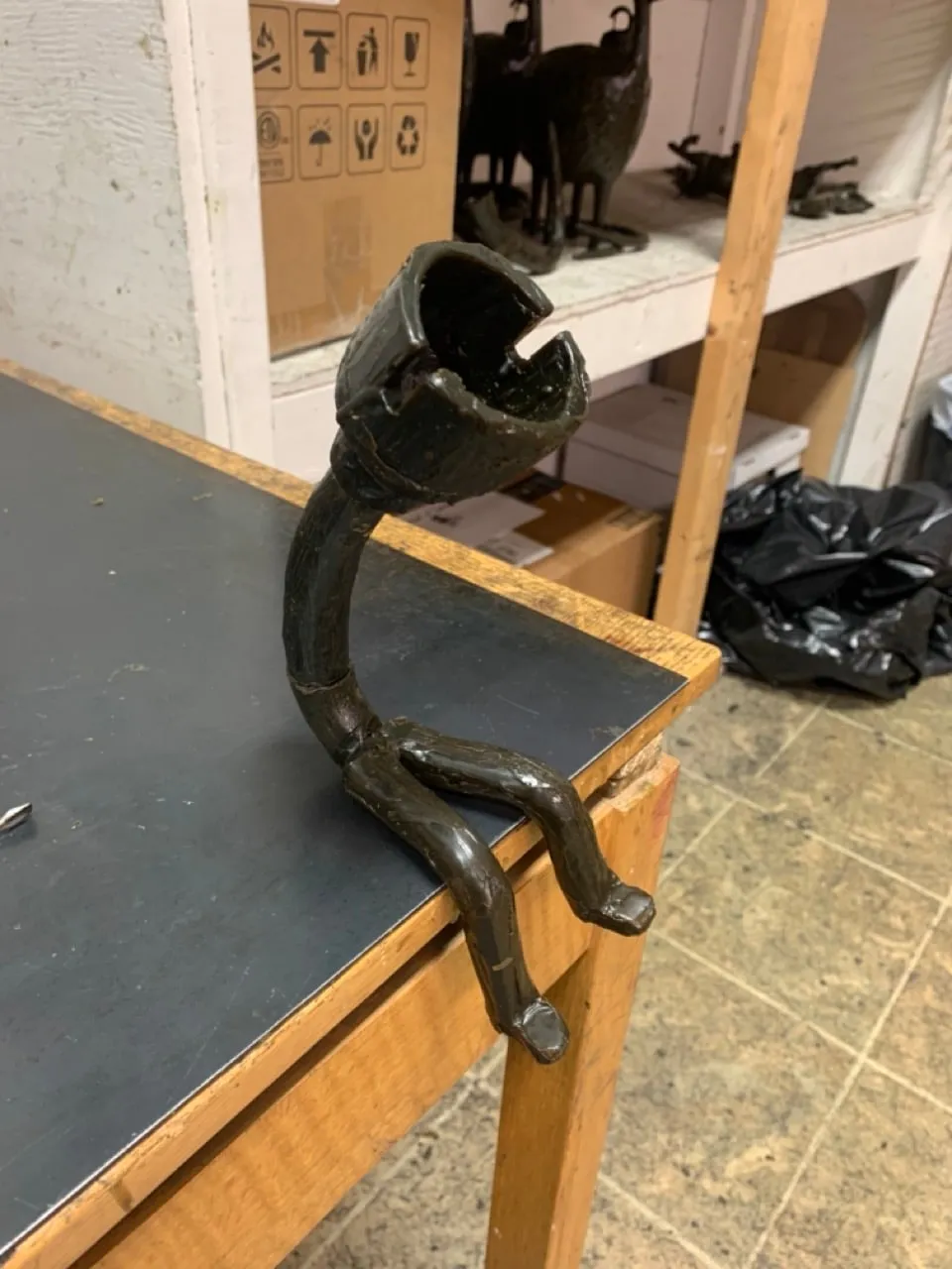 The lamp figure in dark wax, seated on a table edge