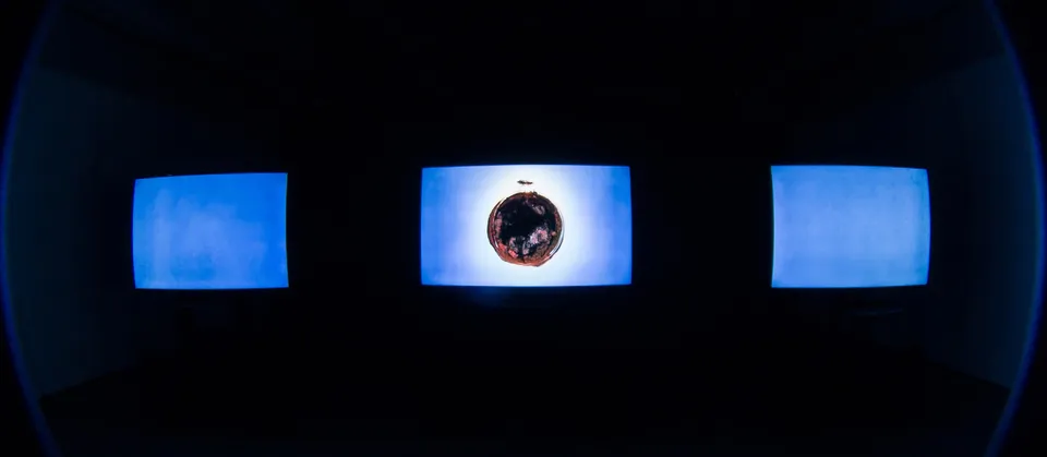 All three screens washed in blue, a small planet on the centre screen